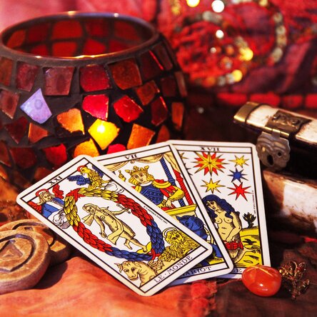 Komposition von verschiedenen Gegenständen auf einem Tisch, die für das Wahrsagen verwendet werden - u. a. drei Tarot-Karten.