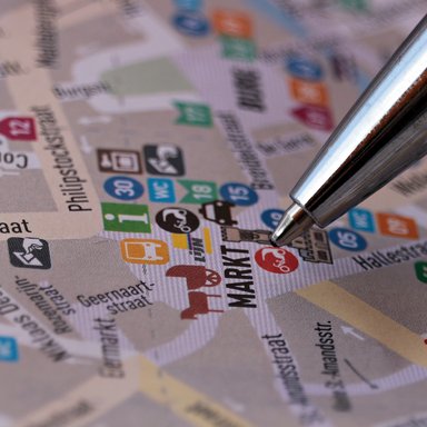 Eine Kugelschreiberspitze zeigt auf einen Punkt in einem Stadtplan.