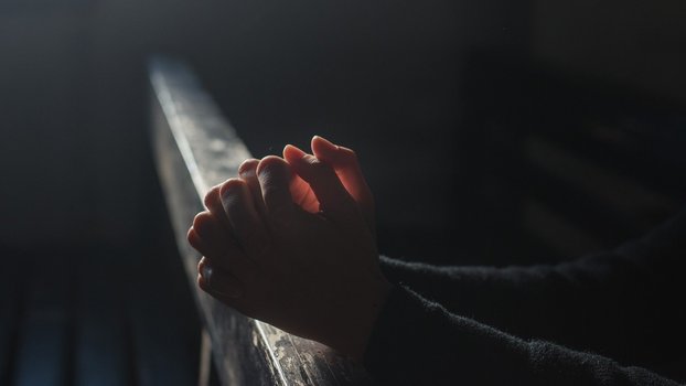 Zum Gebet gefaltete Hände auf die ein Lichtstrahl fällt.